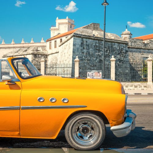HAVANA,CUBA - APRIL 21, 2015 : Vintage american car parked next to an old colonial castle